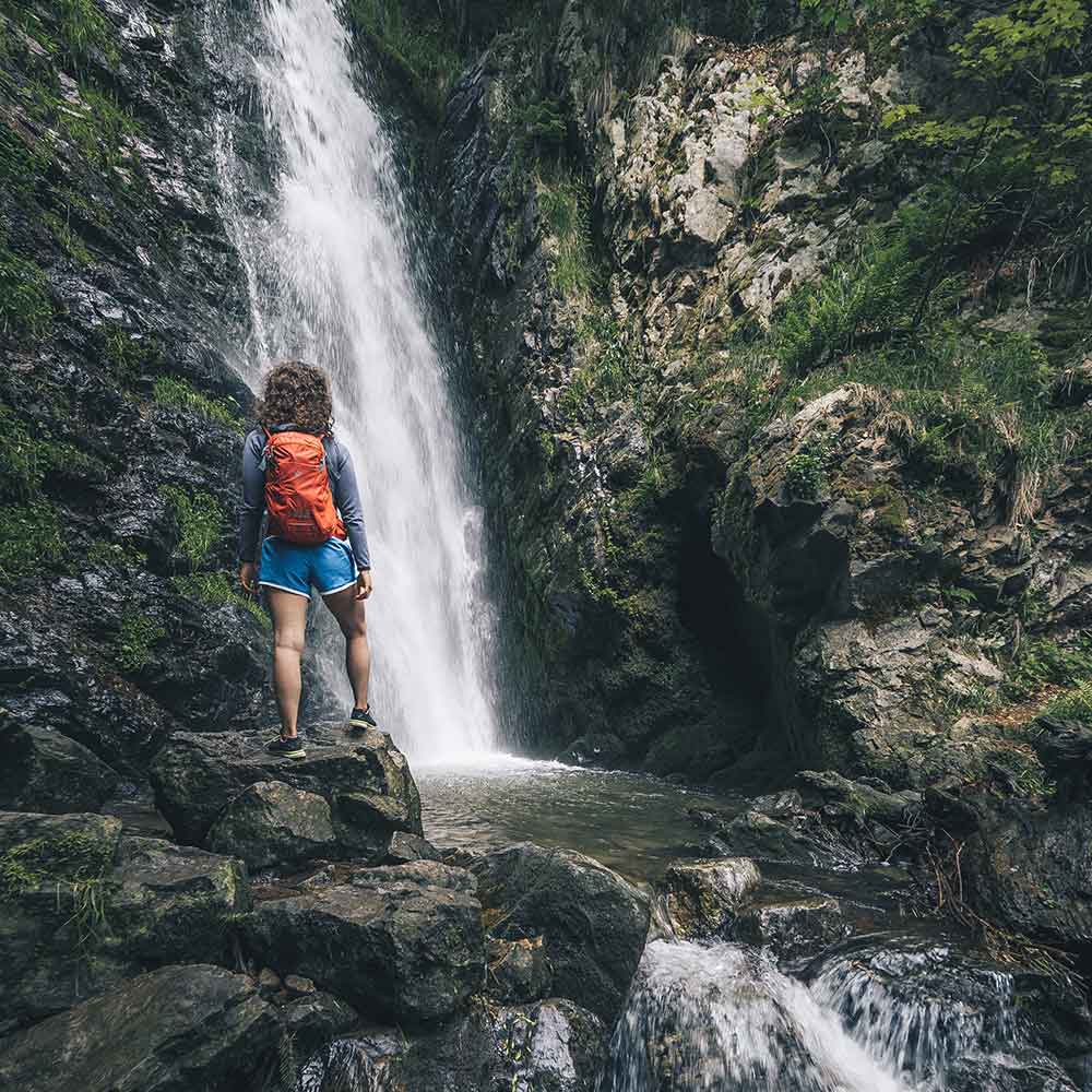 Frau steht vor einem Wasserfall